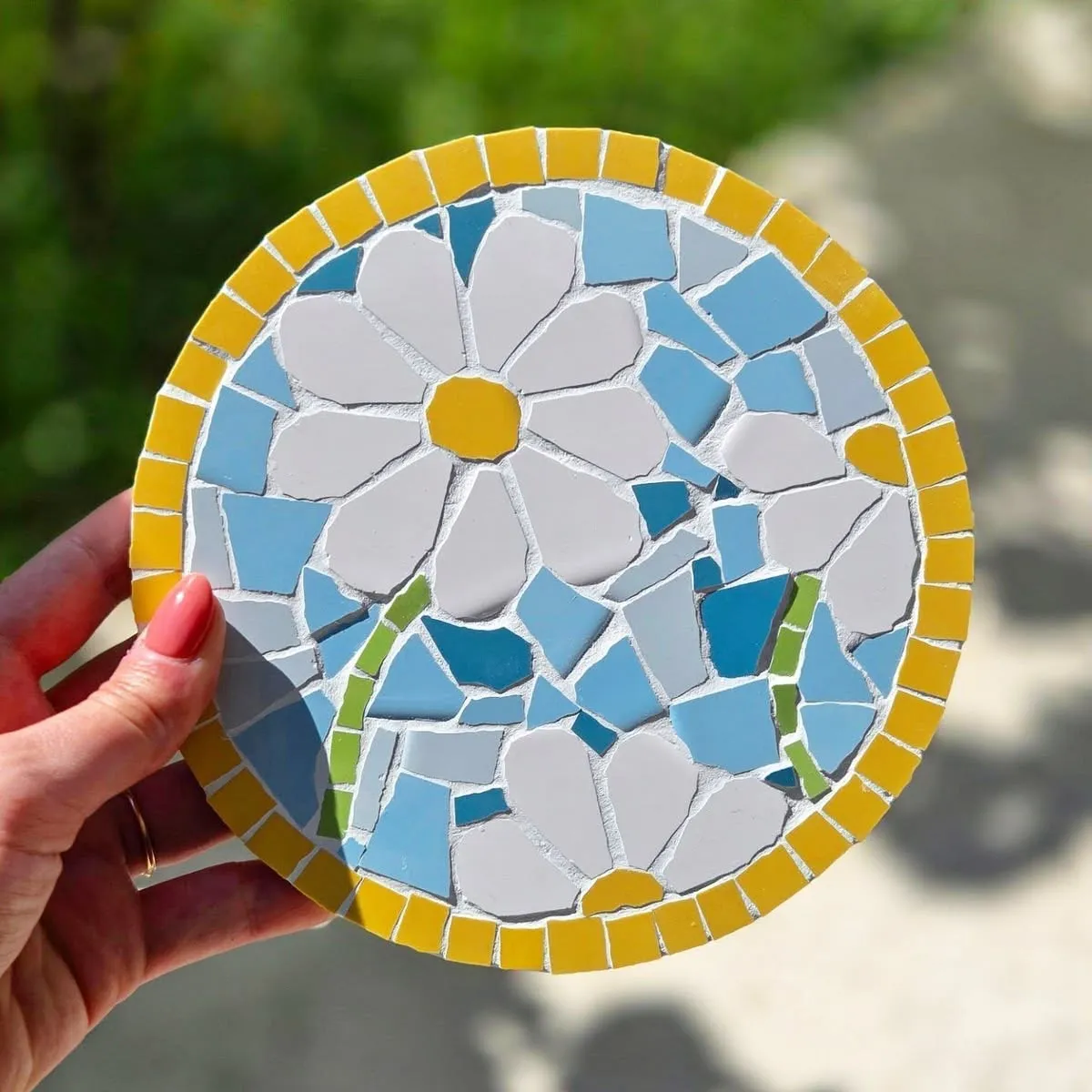 Ronde bloemenmozaïek in de hand, gemaakt tijdens een creatieve verjaardagsworkshop