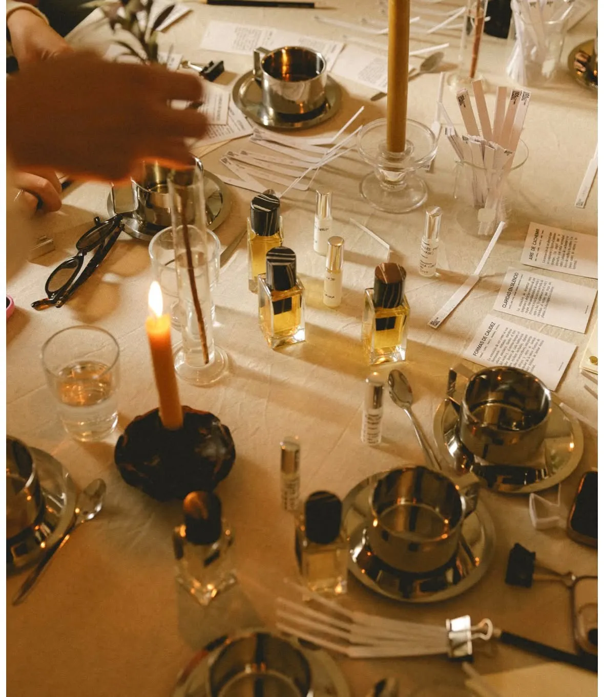 Tafel van de parfum workshop met essenceflesjes, proefstrookjes en een brandende kaars