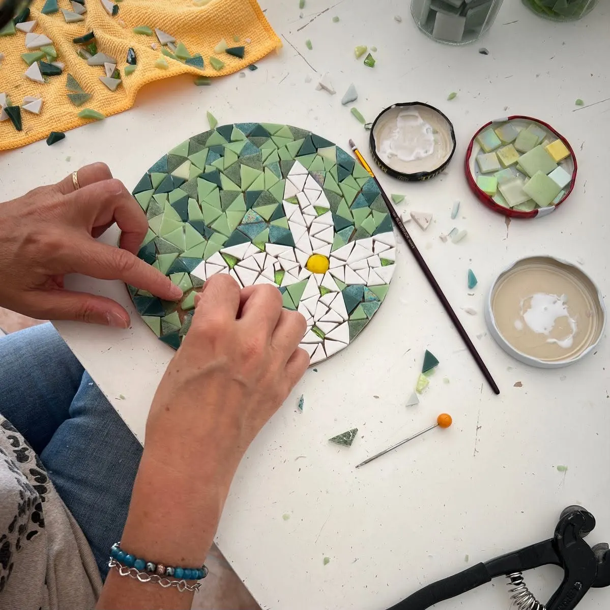Deelneemster die een bloemvormige mozaïek legt tijdens een creatieve workshop van Break-it in Brussel